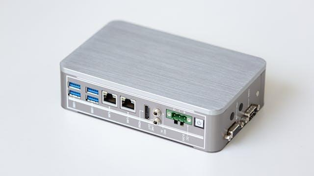 A silver portable router on a wooden surface.